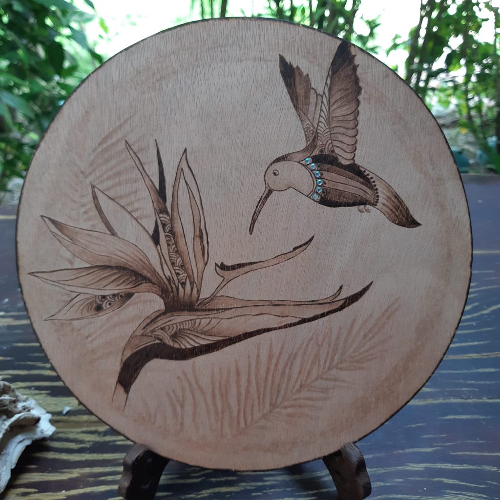 Pyrogravure oiseau volant vers une plante