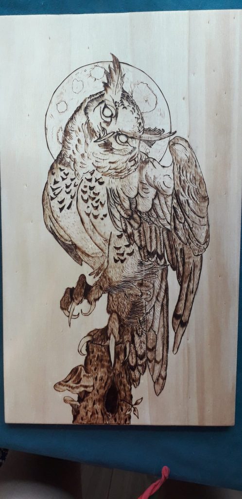 Pyrogravure oiseau sur tronc d'arbre sur fond de lune